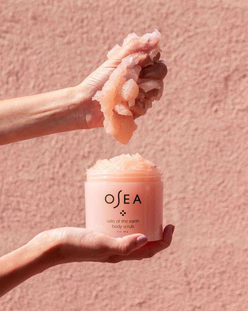 A container of OSEA salts of the earth body scrub with minimalistic design in a pink hue.