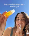 Person applying OSEA oil with a blue sky background