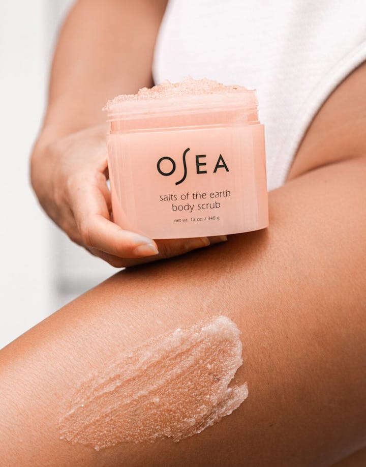 OSEA Salts of the Earth Body Scrub being massaged onto leg with visible grainy texture