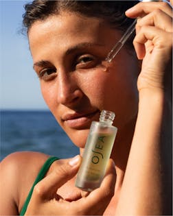 Model applying serum from Ritual Reset Bundle under natural sunlight