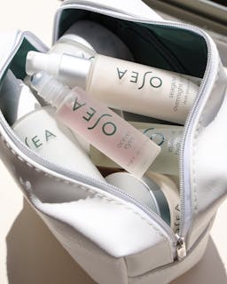 OSEA skincare products in a white makeup bag