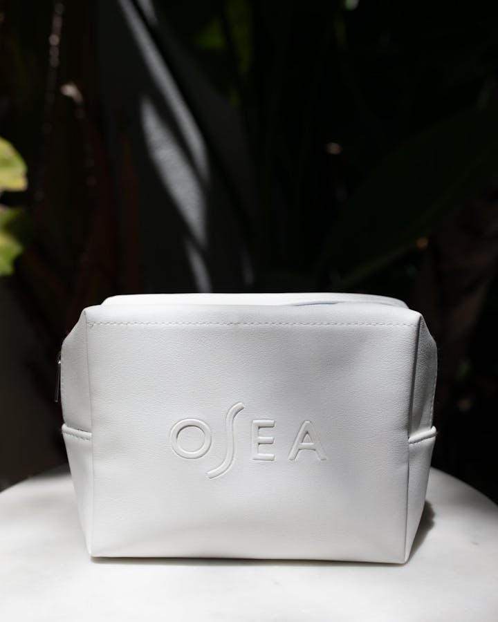 Open OSEA cosmetic bag filled with skincare products including serum, eye treatment, and moisturizer