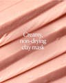 Close-up of creamy pink clay mask texture with text emphasizing non-drying formula