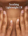 Close-up of hands with 'Soothing Lightweight Oil' text on a brown background