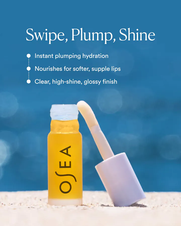 OSEA Hyaluronic Lip Oil Booster rollerball standing open in sand against a blue background, with text reading 'Swipe, Plump, Shine: Instant plumping hydration. Nourishes for softer, supple lips. Clear, high-shine, glossy finish.