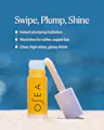 OSEA Hyaluronic Lip Oil Booster rollerball standing open in sand against a blue background, with text reading 'Swipe, Plump, Shine: Instant plumping hydration. Nourishes for softer, supple lips. Clear, high-shine, glossy finish.