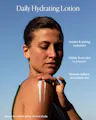 Close-up of a woman applying OSEA Undaria Algae Body Lotion to her shoulder against a blue sky, with text reading 'Daily Hydrating Lotion: Instant & lasting hydration. Visibly firms skin in 4 hours. Reveals radiant, revitalized skin,' based on a third-party clinical study.
