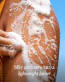 Person applying foamy gel to their skin with a blue background