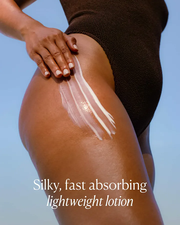 Close-up of OSEA Undaria Algae Body Lotion swiped onto a hip against a blue sky, with text reading 'Silky, fast absorbing lightweight lotion.
