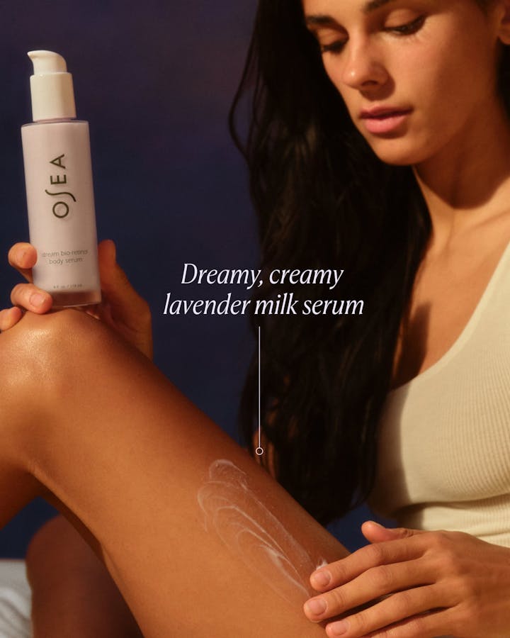 Woman applying OSEA lavender milk serum to her arm with a dark background