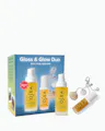 OJEA Gloss & Glow Duo gift set featuring a blue and yellow box, a body oil bottle, a body cream bottle, and a lip oil tube with decorative seashell charms, on a white background.