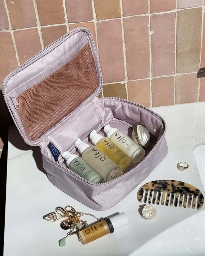 Travel beauty pouch with OSEA minis and lip oil keychain styled on vanity
