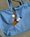 OSEA lip oil keychain clipped onto light blue tote bag