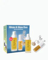 OJEA Gloss & Glow Duo gift set featuring a blue and yellow box, a body oil bottle, a body cream bottle, and a lip oil tube with decorative seashell charms, on a white background.