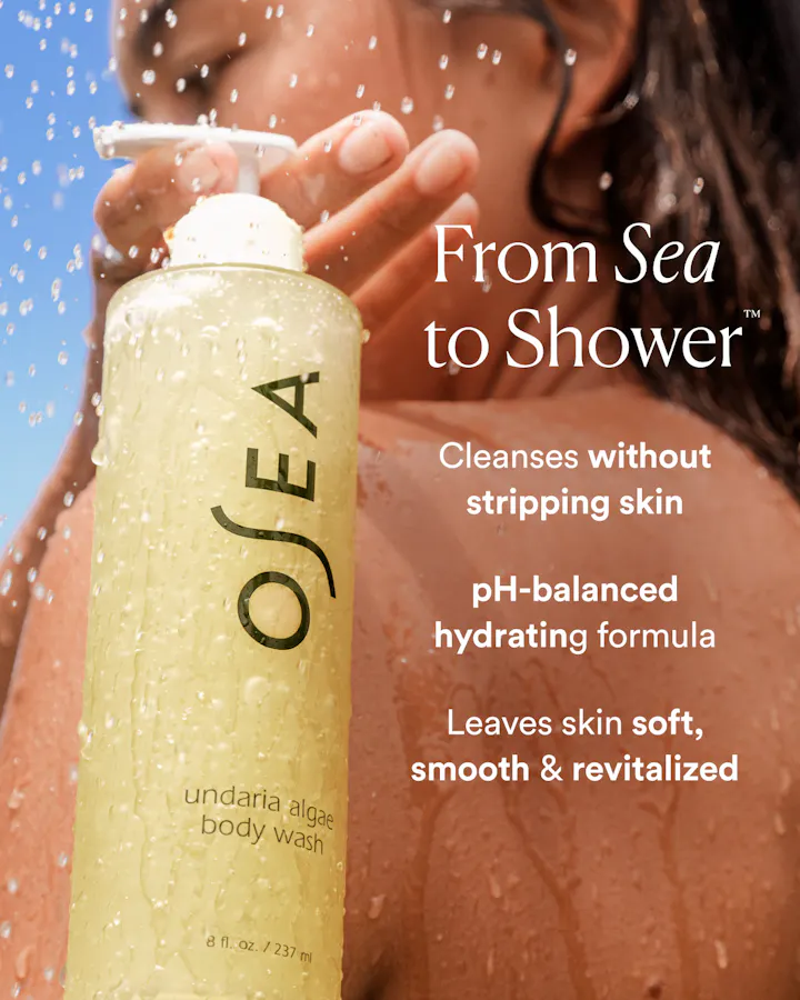 OSEA body wash bottle with text about product benefits on a blurred shower background