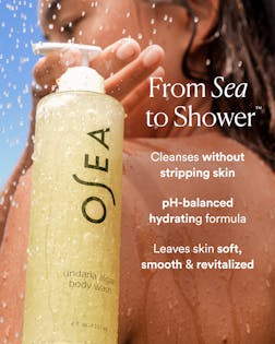 OSEA body wash bottle with text about product benefits on a blurred shower background