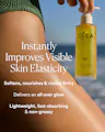 OSEA body oil bottle with text about skin elasticity improvement against a blurred beach background