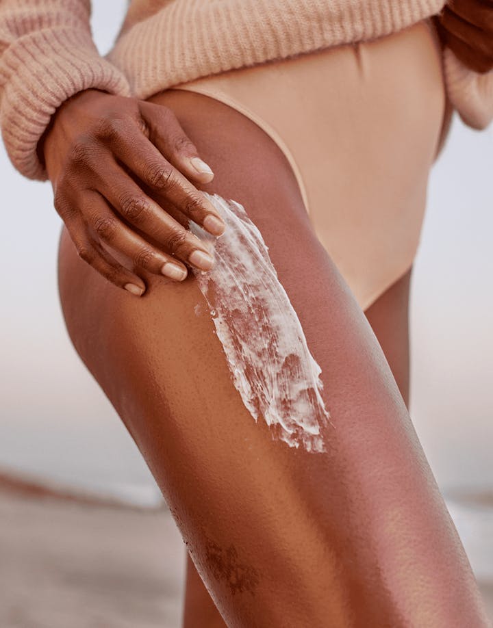 Person applying sunscreen to their leg with a hand