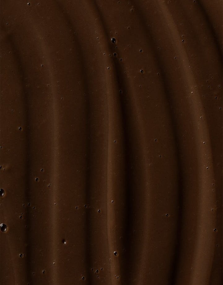 Close-up of rich, dark brown Ocean Cleansing Mudd texture with wavy surface pattern