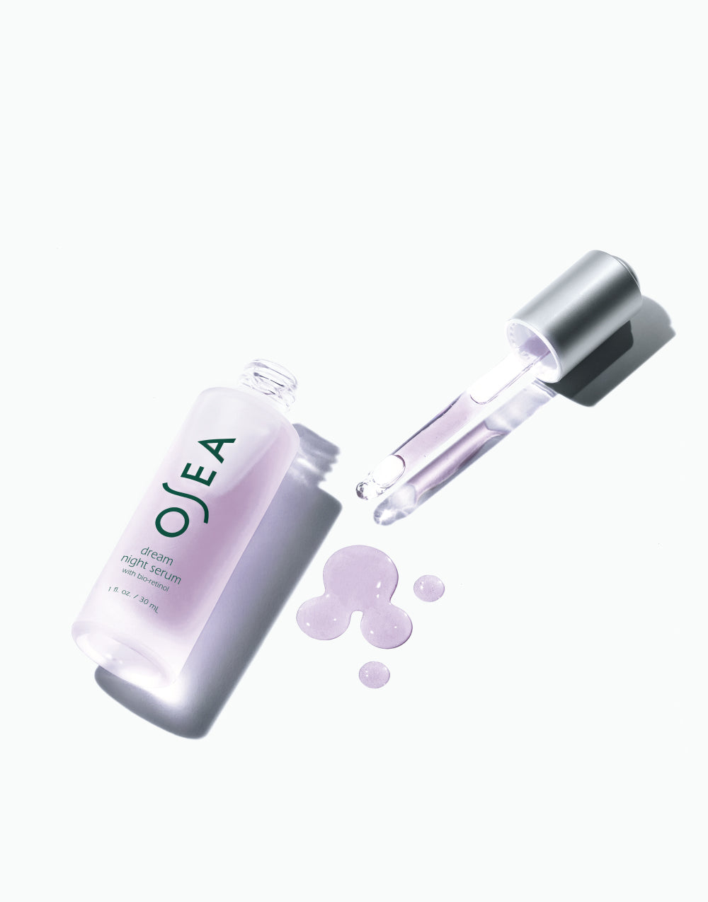 OSEA Dream Night Serum bottle next to silver dropper on pastel background