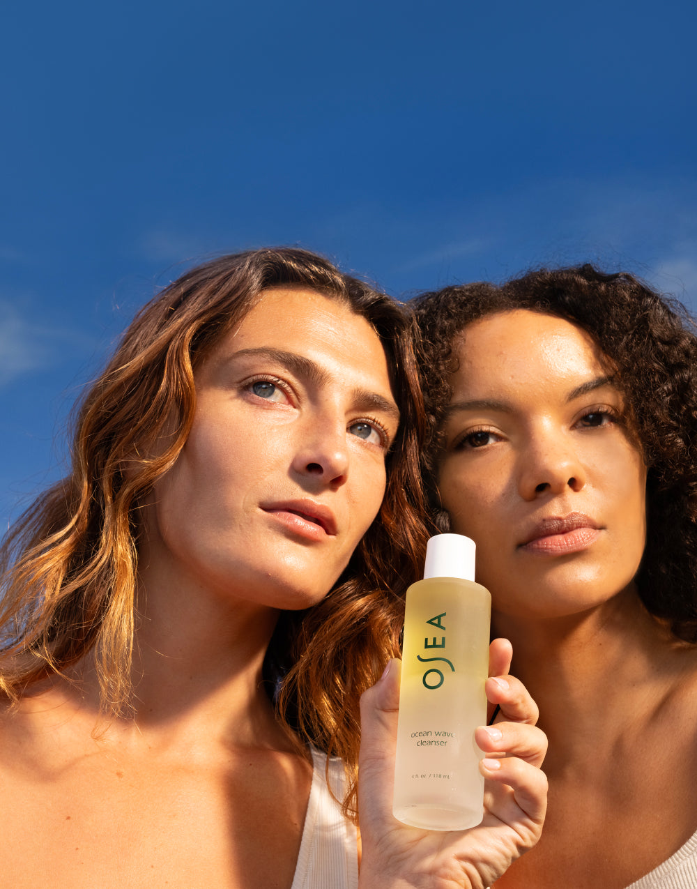 Two models holding OSEA Ocean Wave Cleanser under natural sunlight