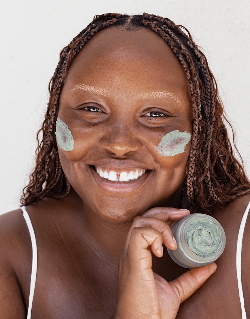 Close-up of model holding Seaglow jar while wearing scrub on cheeks