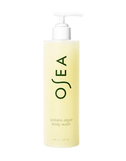 A pump bottle of OSEA body wash with a light yellow hue and green text, labeled 'undaria algae body wash'.