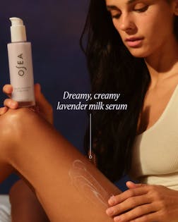 Woman applying Osea lavender milk serum to her arm with a dark background