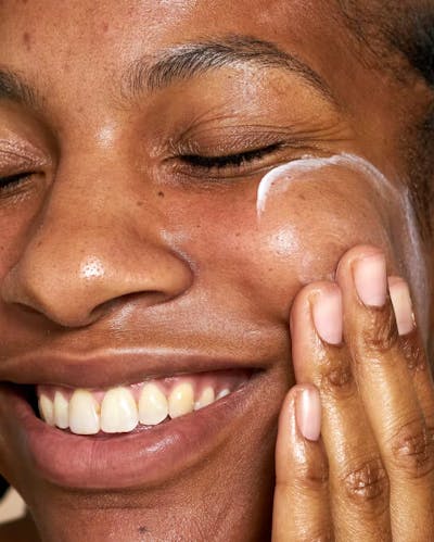 Woman Applying Cream To Her Face