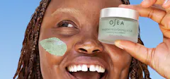 Woman Holding Up A Jar Of Exfoliant