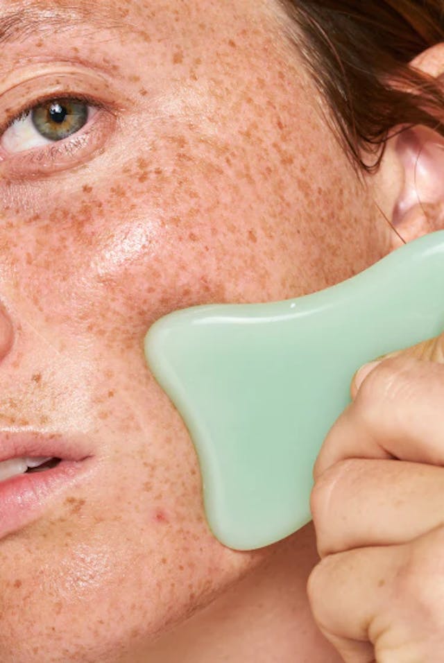 Woman Uses A Green Gua Sha Facial Tool