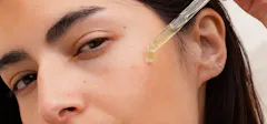 A Woman Applying A Serum To Her Face