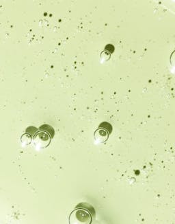 Swatch of Hyaluronic Sea Serum with visible suspended micro-droplets on light surface