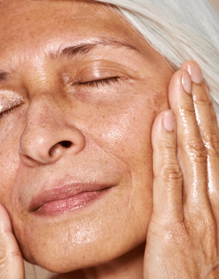 Mature model applying oil with serene expression, highlighting glow