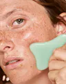 Close-up of model using mint green OSEA sculpting tool along cheek for facial massage