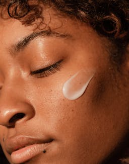 Model with eyes closed applying Seaglow Overnight Serum to cheek