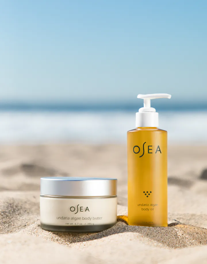 Undaria Body Butter and Body Oil styled on beach to evoke radiant, sunlit hydration